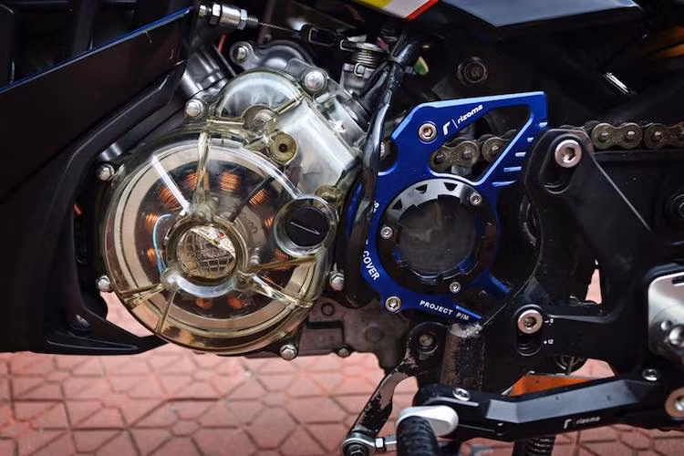 Với cặp bánh lớn, "nội công" của chiếc Yamaha Exciter 150 cũng đã được độ lại. Ở bên ngài, động cơ của xe nổi bật bởi hàng loạt các "đồ chơi" độc đáo như bưởng điện trong suốt bằng nhựa, bưởng côn với cửa sổ trong suốt "made in Vietnam" và "mang cá" chắn nhông Rizoma.