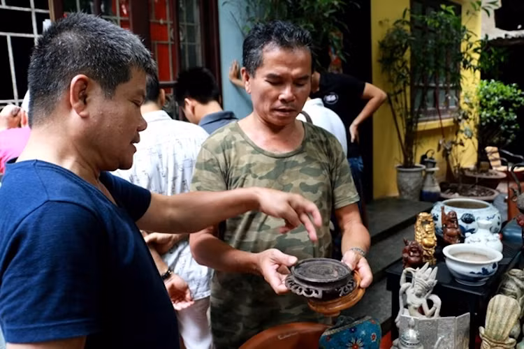 Những người mê đồ cổ cùng nhau xem và thẩm định giá trị của một món đồ.