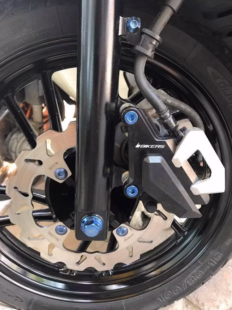 Toàn bộ các chi tiết sơn bạc trên chiếc SH nguyên bản như mâm, bưởng máy... cũng đã được chủ xe sơn lại trong màu đen mờ mạnh mẽ. Hệ thống phanh trước nguyên bản của xe được giữ nguyên heo Nissin 3 piston, nhưng có đĩa độ của Galfer và bảo vệ heo phanh từ hãng Bikers (Thái Lan).