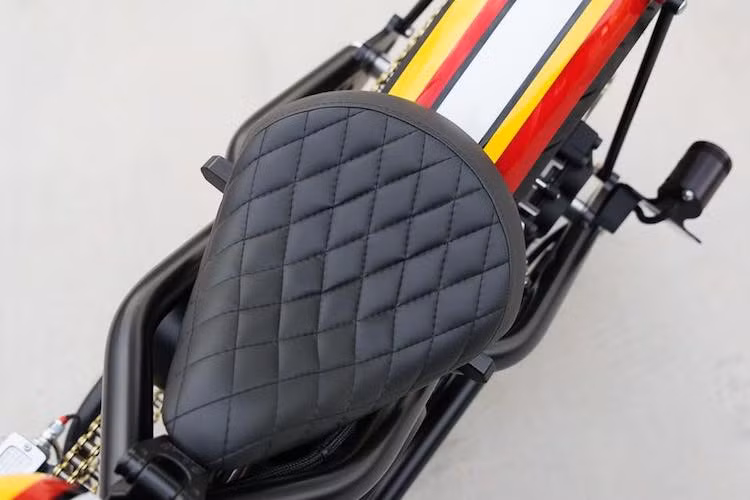 Theo phong cách bobber, chiếc xe đã được gắn một bộ yên solo mỏng với bề mặt chần chỉ vân con thoi đẹp mắt. Phía sau yên là bộ chắn bùn cắt ngắn, được hoàn thiện với lớp sơn gồm các họa tiết kẻ sọc chạy dọc từ bình xăng xe xuống.