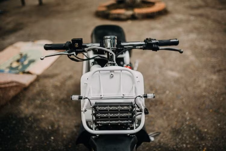 Đặc trưng của mẫu xe máy Zoomer 50cc là cụm đèn pha kép phía trước đã được MTK loại bỏ trên bản độ này. Thay vào đó, xưởng độ đã trang bị cho chiếc xe dàn đèn pha LED 3 hàng phía trước siêu sáng, kết hợp cùng với cặp đèn xi-nhan Rizoma Drop cho phần đầu xe.