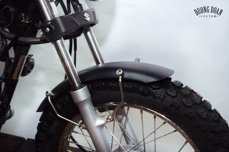 Trên bản độ này, cặp vành nan kèm phanh đùm nguyên bản của GD110 với đường kính 17 inch vẫn được xưởng độ giữ nguyên để giữ "chất" cổ điển. Tuy nhiên với dè trước ngắn và cặp lốp gai, chiếc xe đã có dáng địa hình "phong trần" hơn.