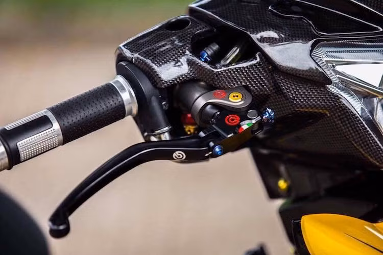 Toàn bộ phần vỏ đầu của chiếc xe máy Yamaha Exciter nguyên bản đã được bao phủ bên ngoài bởi sợi carbon thật, đem tới "chất" xe đua cho bản độ. Ở bên trái tay lái là sự hiện diện của cùm phanh Brembo Billet đẳng cấp và bình dầu giấu gọn.