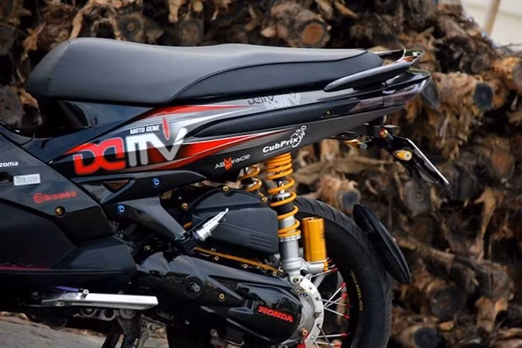 Ở phía sau, hệ thống phuộc nguyên bản đã được độ lại khá "khủng" với cặp phuộc Ohlins bình dầu rời. Trong khi đó, động cơ Air Blade không có sự thay đổi, ngoại trừ lốc máy sơn màu đen bóng cùng một số con ốc Proti trang trí. Toàn bộ dàn vỏ xe nay đã sơn tem đấu với tông màu đỏ-đen bí ẩn và thể thao.