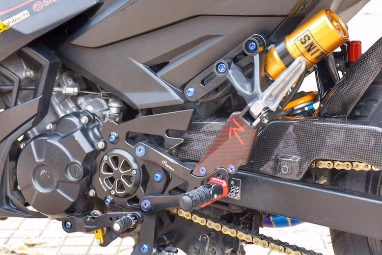 Mang cá chắn nhông của xe đã được thay bằng loại nhôm CNC của Shark Power, tạo thêm điểm nhấn cho bản độ. Trong khi đó, chủ xe đã thay cho Exciter dàn để chân Lightech R vốn dành cho các siêu môtô phân khối lớn, khiến cho tư thế ngồi của chiếc xe có thể được thay đổi dễ dàng hơn và giảm trọng lượng.