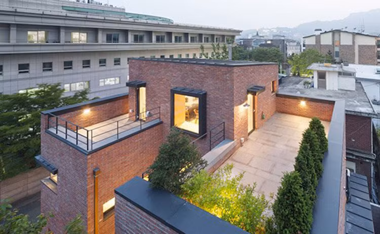 Với những bức tường gạch mộc màu đỏ đô, rõ ràng, dù đơn giản nhưng ngôi nhà vẫn nổi bật hơn hẳn những công trình xung quanh đó.