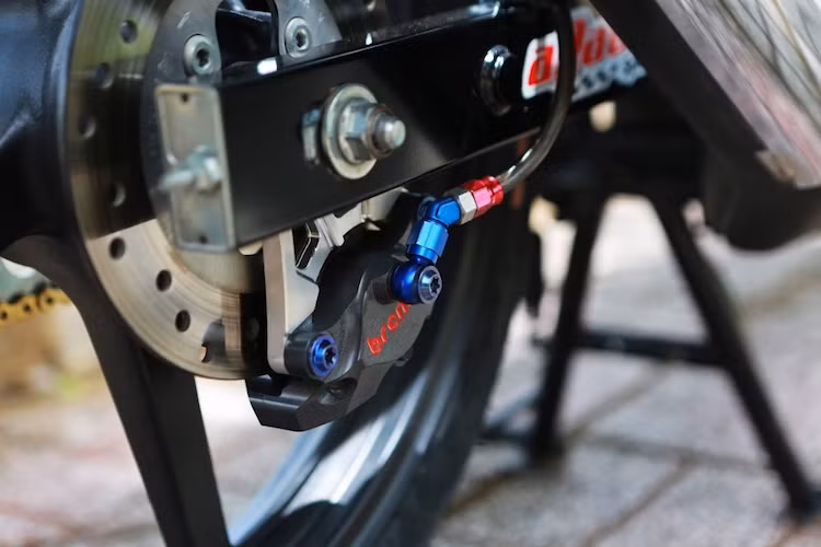 Trong khi đó, hệ thống phanh phía sau cũng đã được độ lại "khủng" không kém phanh trước với dây dầu Earl's và heo Brembo 2 pis đối xứng. Một điểm khá độc đáo của bản độ này đó là thay vì mâm 6 cánh kép nguyên bản của Sonic 150R, chủ xe đã "xuống đời" với mâm 5 cây từ Sonic 125 đời cũ, tạo vẻ độc đáo và khỏe khoắn cho chiếc xe.