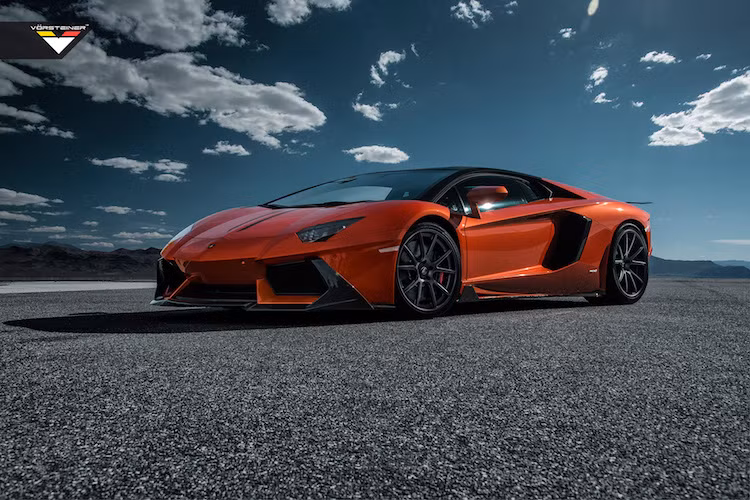 Chiếc siêu xe Lamborghini Aventador màu cam đã trở nên ấn tượng hơn so với "đồng loại" khi được trang bị các chi tiết bằng sợi carbon trần tương phản, nằm trong gói độ Zarazoga của Vorsteiner.