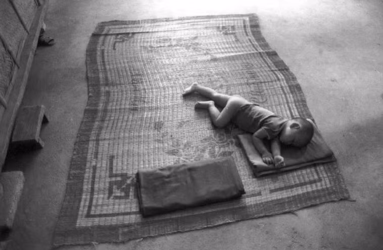 Giấc ngủ trên nền nhà của em bé nông thôn. Ảnh: Ferdinando Scianna/ Magnumphotos.com.