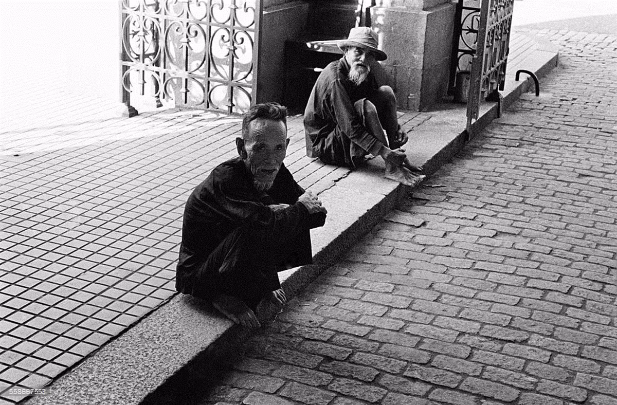 Hai ông lão hành khất ngồi trước cửa Nhà thờ Đức Bà. Ảnh: Getty.