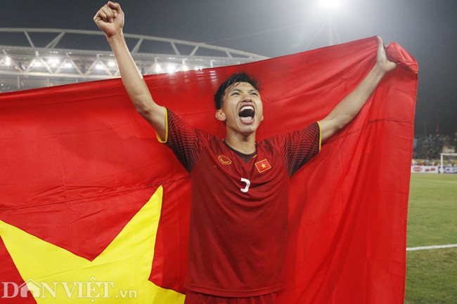 Văn Hậu, cầu thủ trẻ nhất đội tuyển Việt Nam, giương cao lá cờ trên sân vận động Mỹ Đình.