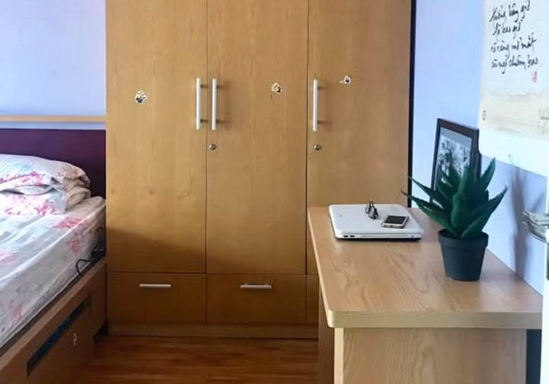 Trong phòng ngủ của 2 vợ chồng, chiếc tủ quần áo to được đặt ở giữa. Bên cạnh là bàn làm việc. Chiếc bàn đã cũ, có vẻ như lâu ngày chưa được sử dụng.