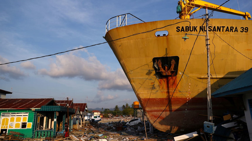 Một con tàu cỡ lớn bị cơn sóng đưa lên bờ, ngay sát nhà dân. Cơn sóng thần diễn ra vào gần lễ Giáng sinh khiến cho nhiều người nhớ đến trận sóng thần lịch sử tàn phá Indonesia vào ngày 26/12/2004. Ảnh: Reuters.