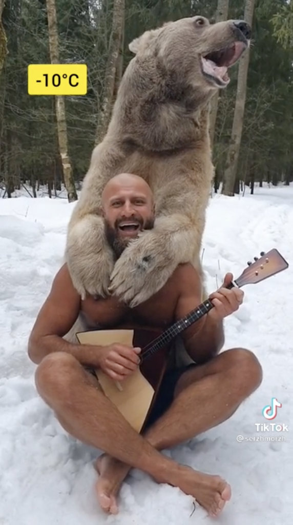 Người đàn ông dũng cảm cởi trần chơi đàn cùng gấu nâu dưới cái lạnh -10 độ C. Ảnh: IT.
