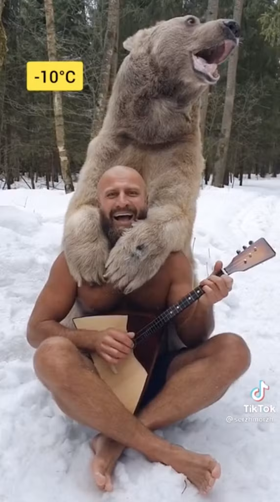 Người đàn ông dũng cảm cởi trần chơi đàn cùng gấu nâu dưới cái lạnh -10 độ C. Ảnh: IT.