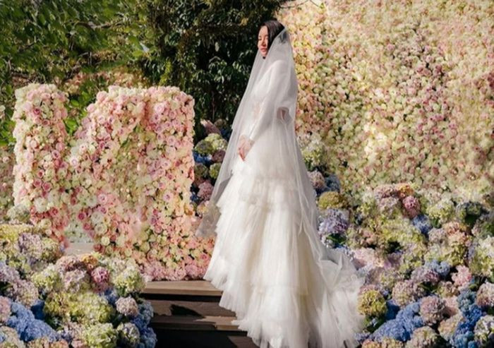 Cô dâu xinh đẹp đứng giữa không gian được phủ đầy các loại hoa tươi rực rỡ.