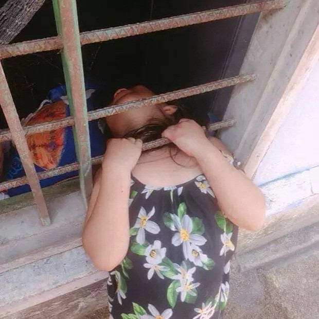 Không hiểu bằng cách nào mà bé gái có thể đưa đầu chui qua thanh chắn cửa sổ.