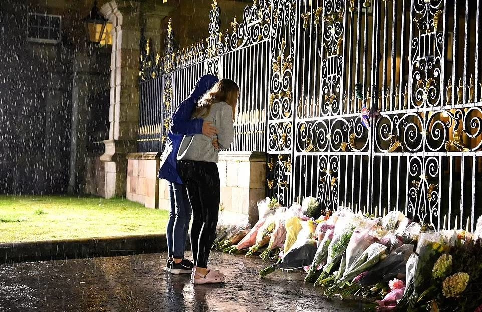 Hai cô gái đội mưa đến đặt hoa tưởng nhớ bên ngoài cổng lâu đài Hillsborough, nơi ở của Nữ hoàng Elizabeth II khi bà đến Bắc Ireland.