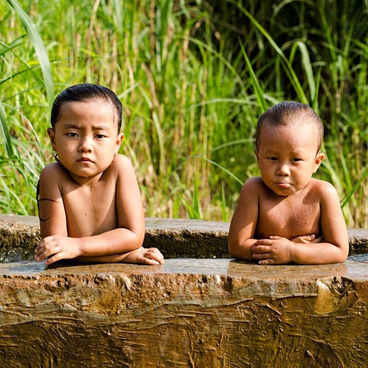 Hai em bé ở vùng nông thôn Việt Nam tắm mát giữa ngày Hè.