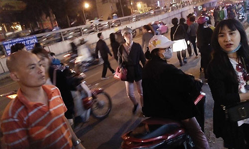 Cô gái (ngồi xe máy) bức xúc do chủ điểm trông giữ xe tự phát thu thêm tiền, dù trước đó đã trả.