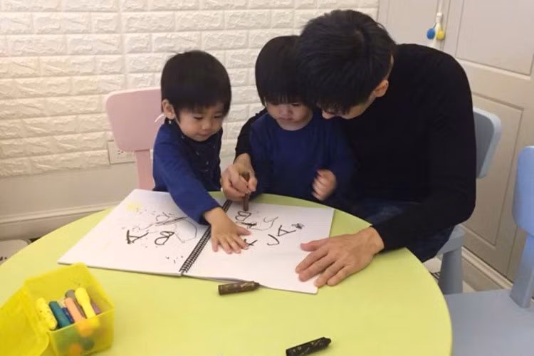 Hình ảnh Lâm Chí Dĩnh hướng dẫn con trai tập viết chữ cái tiếng Anh.