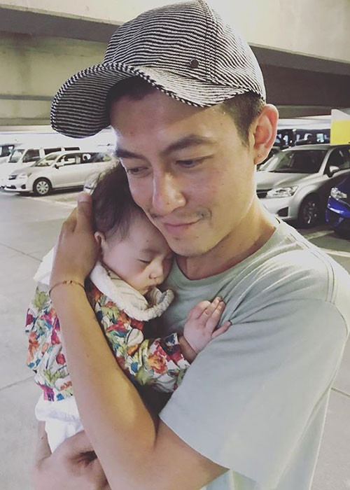 Hình ảnh Trần Quán Hy mỉm cười, ôm con gái vào lòng.