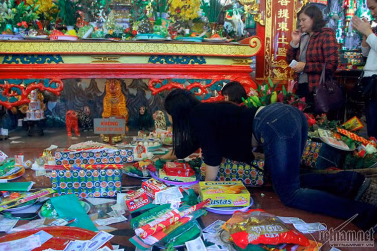 Ai cũng cố gắng chen chân để đặt được mâm lễ của mình gần điện thờ chính của phủ Tây Hồ. Một phụ nữ cố trườn người để đưa mâm lễ vào sâu bên trong.