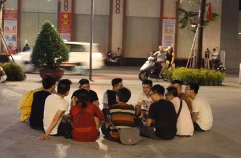 Nhiều bạn trẻ ngồi tụm lại trò chuyện, đàn hát vui vẻ.