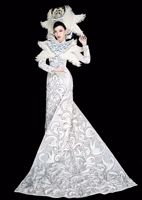 NTK Minh Châu chia sẻ về bộ quốc phục của Ái Nhi: “Đây là hình ảnh mà Châu đã khắc họa bằng kỹ thuật 3D, lấy hình ảnh phượng hoàng để thể hiện trên bộ áo dài màu trắng. Khi Nhi diện bộ trang phục này, Châu mong rằng Nhi sẽ thể hiện được vẻ uy lực, uy quyền của một bộ quốc phục. Bên cạnh đó giúp Nhi khẳng định được mình trên sân khấu cũng như cho bạn bè quốc tế có cái nhìn đặc biệt và bất ngờ hơn về tà áo dài Việt Nam”. Ảnh: Hoàng Phúc