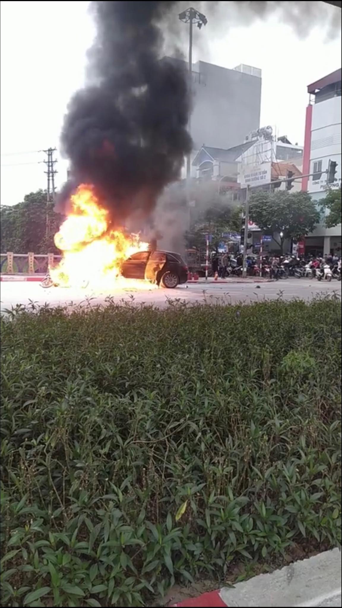 Sau vụ tai nạn, chiếc xe máy nằm gọn trước đầu xe Mercedes và chiếc xe ô tô nhãn hiệu hạng sang này bất ngờ bốc cháy dữ dội.