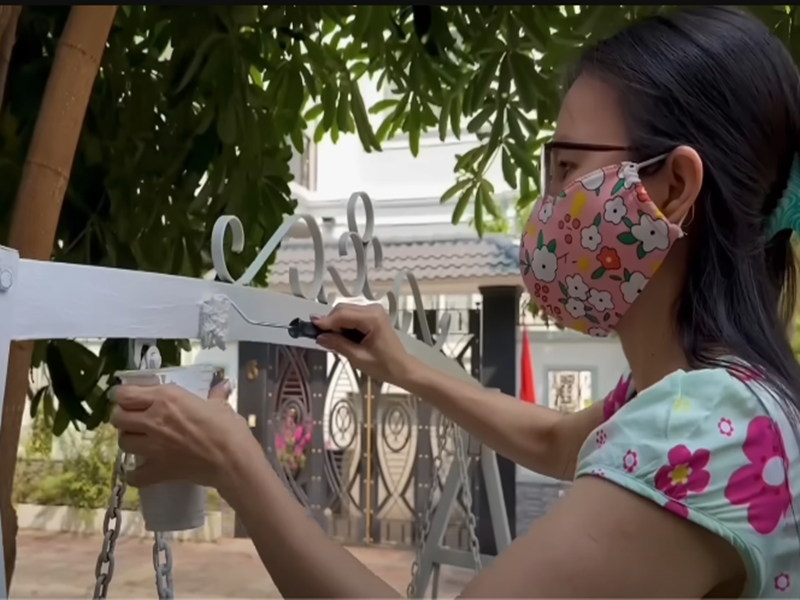 Nữ ca sĩ tự tay sơn lại chiếc xích đu ngoài sân. Ảnh: Youtube Cẩm Ly.