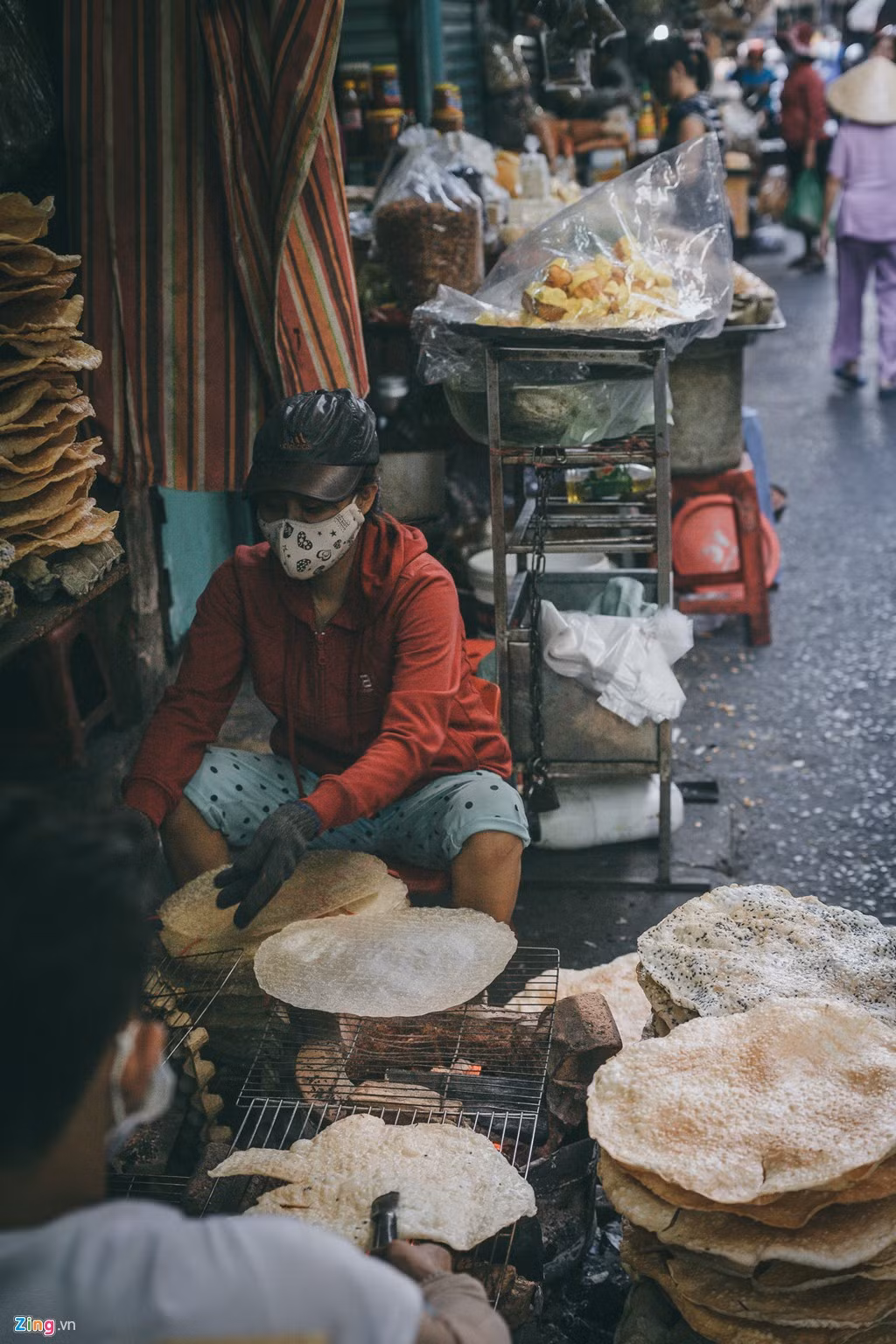 Trong ảnh, hai anh em Đinh Văn Dũng và Đinh Thị Thuý đang nướng bánh tráng bên bếp than đỏ lửa, trước cửa hàng của mình dưới nắng chiều gay gắt.