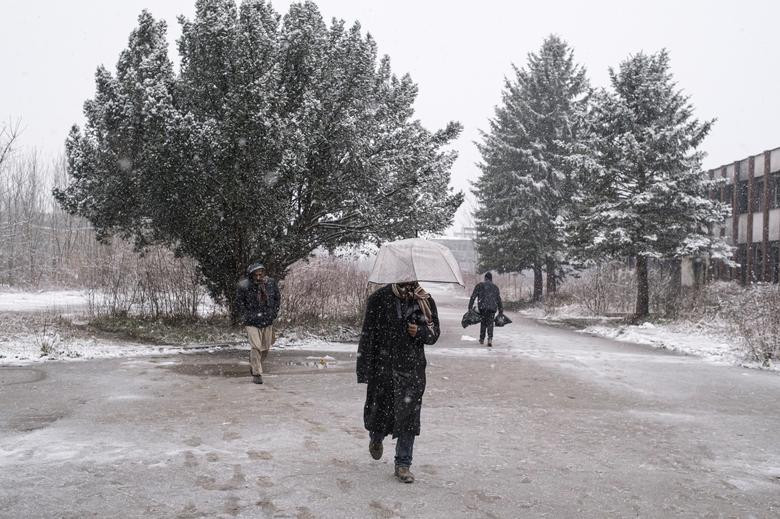 Một số di dân đi dưới trời mưa tuyết.