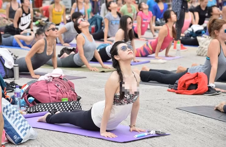 Trong hình, cô gái diện áo hai dây tập yoga ở chốn đông người.