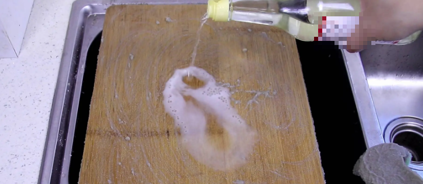 Sau khi lau sạch, chúng ta đổ một ít giấm trắng lên trên. Tác dụng của giấm trắng là khử mùi đặc trưng trên thớt, đồng thời giấm trắng còn có tác dụng làm mềm, có thể làm mềm một số vết nấm mốc trên thớt. Tiếp theo, chúng ta tiếp tục lau bằng miếng cọ rửa, để có thể loại bỏ cả một số vết bẩn cứng đầu.