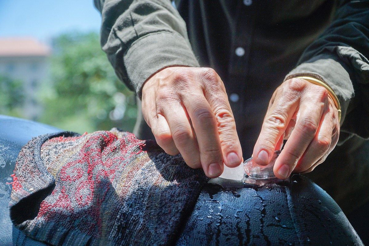 Do phơi nắng quá lâu, một người dân phải dùng khăn ướt, đá lạnh để làm mát yên xe mới có thể tiếp tục di chuyển.