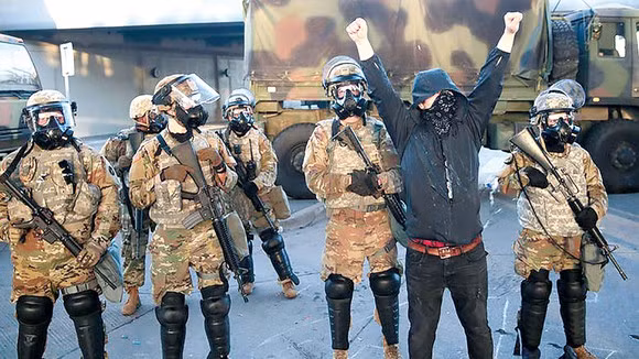 Các binh sĩ Vệ binh quốc gia đứng cạnh một đối tượng quá khích, có thể thấy họ được trang bị cả M-16A2 và M-16A4. Vệ binh quốc gia cũng đã đưa vào sử dụng loại quân phục họa tiết ngụy trang Multicam kiểu mới trong khi áo giáp và mũ chống đạn vẫn là màu họa tiết Digital cũ.