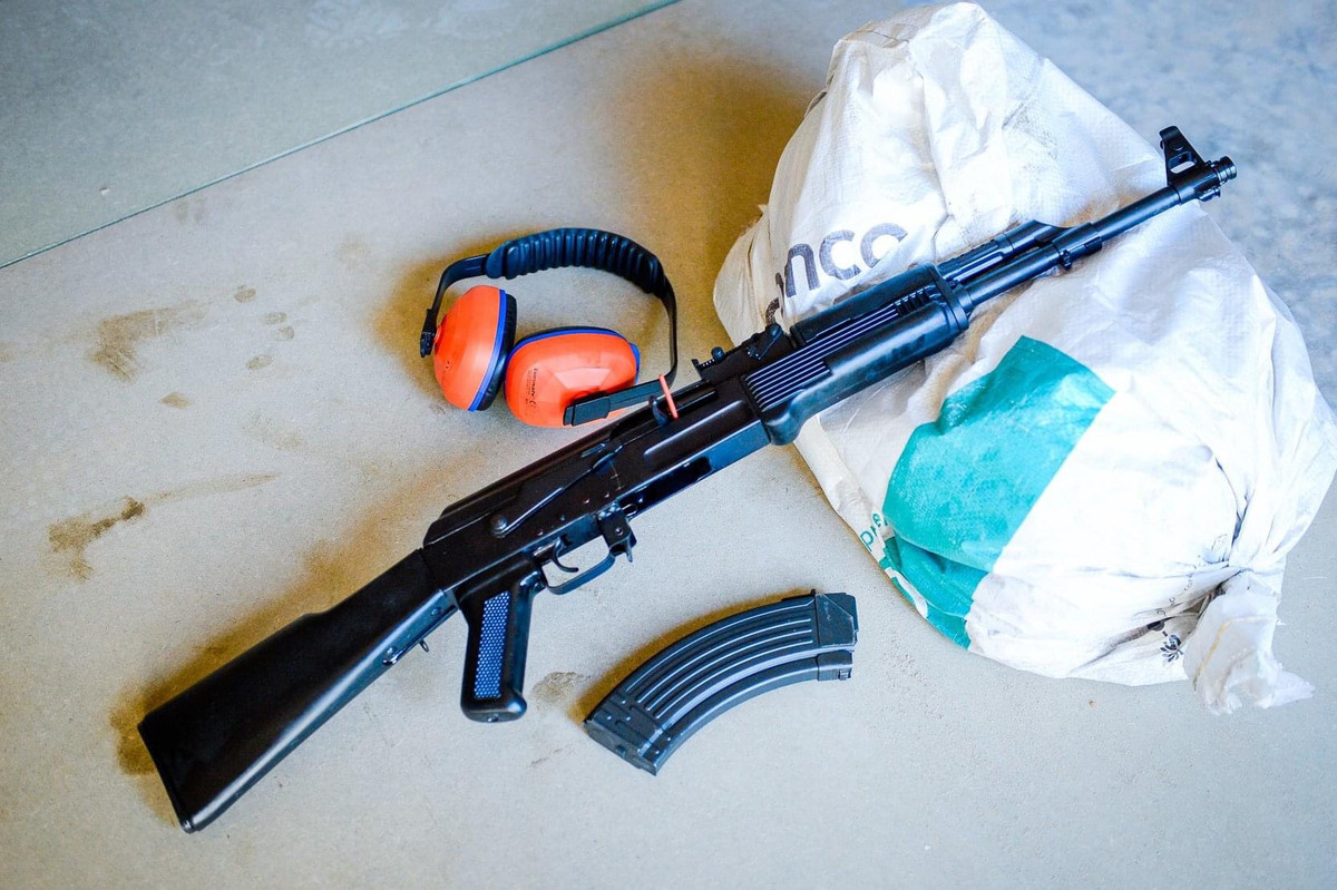 Tuy nhiên báng nhựa của súng lại vẫn giữ phong cách hơi cong xuống giống AK-47 chứ không thẳng như AKM. Đây là một điều khá khó hiểu bởi việc chuyển đổi sang loại báng thẳng như AKM giúp xạ thủ có điểm tì tốt hơn, thuận lợi cho việc tác xạ. Dù vậy, đặc điểm nhỏ này không quá quan trọng, không làm mất đi sức chiến đấu của khẩu súng và có thể khắc phục dễ dàng trong tương lai. Ảnh: Một khẩu AKn mới cứng trên bệ bắn- Nguồn: QPVN.