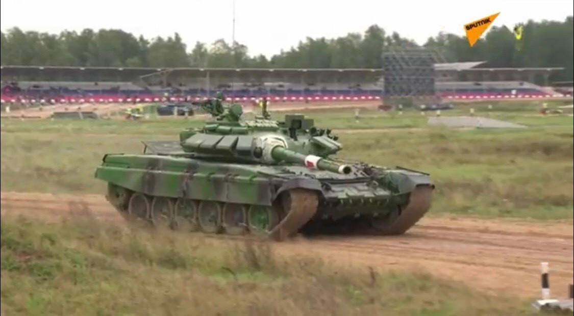 Theo thứ tự, đội tuyển thi đấu đầu tiên sẽ là kíp lái số 1 của Nam Ossetia với chiếc T-72B3 màu xanh lá cây. Sau hồi kèn hiệu lệnh, xe tăng đội bạn nhanh chóng tiến ra đường đua, vượt qua bài di chuyển zic - zắc và đến khu vực tiếp nhận đạn pháo để thực hiện bài bắn pháo 125mm vào 3 mục tiêu giả định xe tăng đối phương. Ảnh: Xe tăng của đội Nam Ossetia tiến vào vị trí nhận đạn.