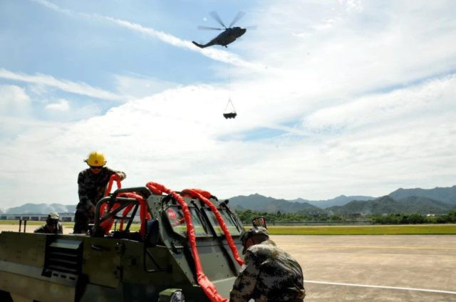 Trong lần đầu tiên xuất hiện chính thức trước công chúng, chiếc trực thăng Z-8L đã trải qua một loạt các bài kiểm tra về việc mang và nâng một xe địa hình 8×8 Bobcat, để kiểm tra tính ổn định và an toàn của quy trình vận chuyển. Ảnh: Trực thăng Z-8L thực hành nâng vật nặng – Nguồn: Snafu-solomon