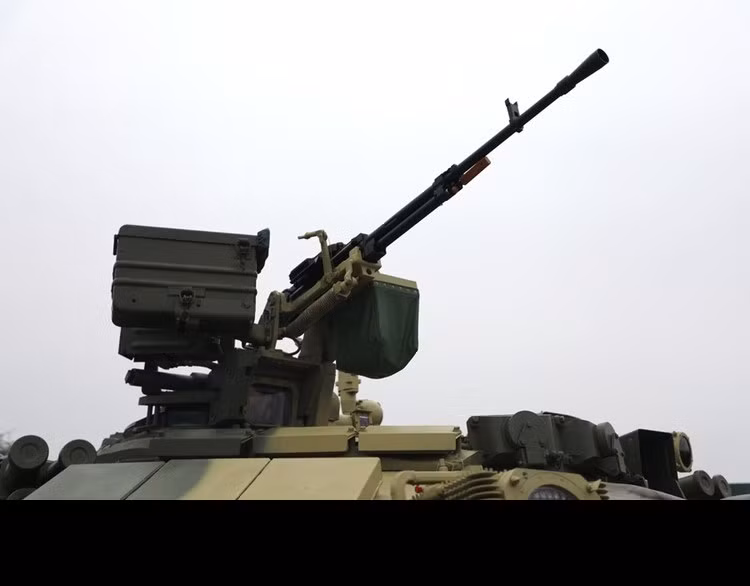 Trên T-90 S/SK lắp đặt cụm súng máy 12.7mm được điều khiển từ trong xe. Trưởng xa có thể sử dụng kính ngắm trưởng xa và kính ngắm phòng không để quan sát và bắt bám mục tiêu, đồng thời có thể nhận được sự trợ giúp từ kính ngắm đa kênh Sosna-U của pháo thủ. Đây là điểm khác biệt lớn giữa T-90 S/SK trong nước và T-72B3 Mod 2011. Dẫu vậy, trong năm nay, các trưởng xa của ta đã khắc phục rất tốt điểm yếu của năm ngoái, sử dụng súng máy 12.7mm vô cùng thuần thục và đã tiêu diệt toàn bộ mục tiêu bia số 25 mô phỏng máy bay trực thăng từ vòng bảng cho đến nay. Ảnh: Cận cảnh súng máy hạng nặng 12.7mm trên nóc T-90 S/SK Việt Nam.