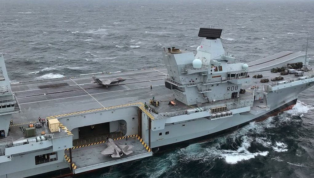 Tàu trang bị một thang máy cho phép triển khai và thu hồi máy bay từ trên boong tàu xuống hầm chứ trong khoang cũng như ngược lại, đồng thời mặt boong được thiết kế theo kiểu nhảy cầu. Ảnh: Thang máy đang chuẩn bị đưa một chiếc F-35B lên mặt boong và một chiếc F-35B khác đang chuẩn bị chạy đà cất cánh trên tàu HMS Queen Elizabeth.