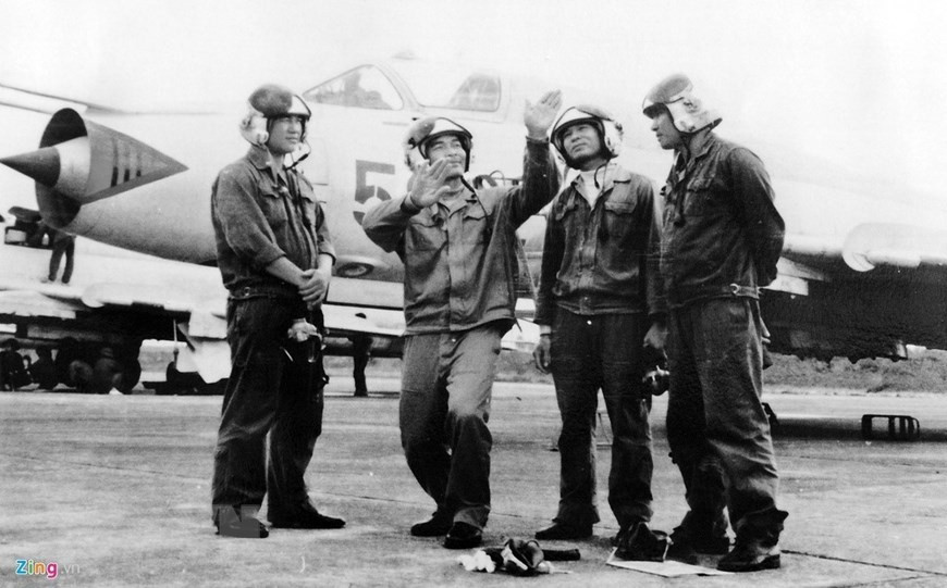 Khi chiếc RA-5C đã hoàn tất nhiệm vụ chụp ảnh trên khu vực các kho xăng dầu và trận địa tên lửa, nghe 2 chiếc F-4 cảnh báo có MiG xuất hiện hướng 8 giờ; hai chiếc F-4 hô cho chiếc RA5C bay thoát ra biển, còn 2 chiếc F-4 sẽ quay lại nghênh chiến. Nhưng đã là quá muộn, bằng động tác cơ động thuần thục, phi công MiG số 2 Hoàng Tam Hùng đã nhanh chóng và khôn khéo, bám được đuôi chiếc RA5C. Ảnh: Phi công MiG-21 trao đổi kinh nghiệp bay - Nguồn: TTXVN