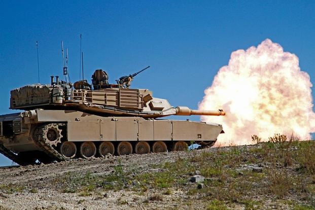 Ở thiết kế xe tăng chiến đấu chủ lực M1 Abrams thế hệ thứ 3 của Mỹ, họ đã quay trở lại sử dụng súng máy 12.7mm lộ thiên được điều khiển trực tiếp bởi trưởng xe, có chăng để đảm bảo độ bảo vệ tốt hơn cho chiến sĩ, người ta đã bổ sung thêm các tấm chắn chống đạn cho xạ thủ. Ảnh: Xe tăng M1 Abrams khai hỏa pháo chính, có thể thấy khẩu súng máy .50cal ở trên nóc được điều khiển lộ thiên.