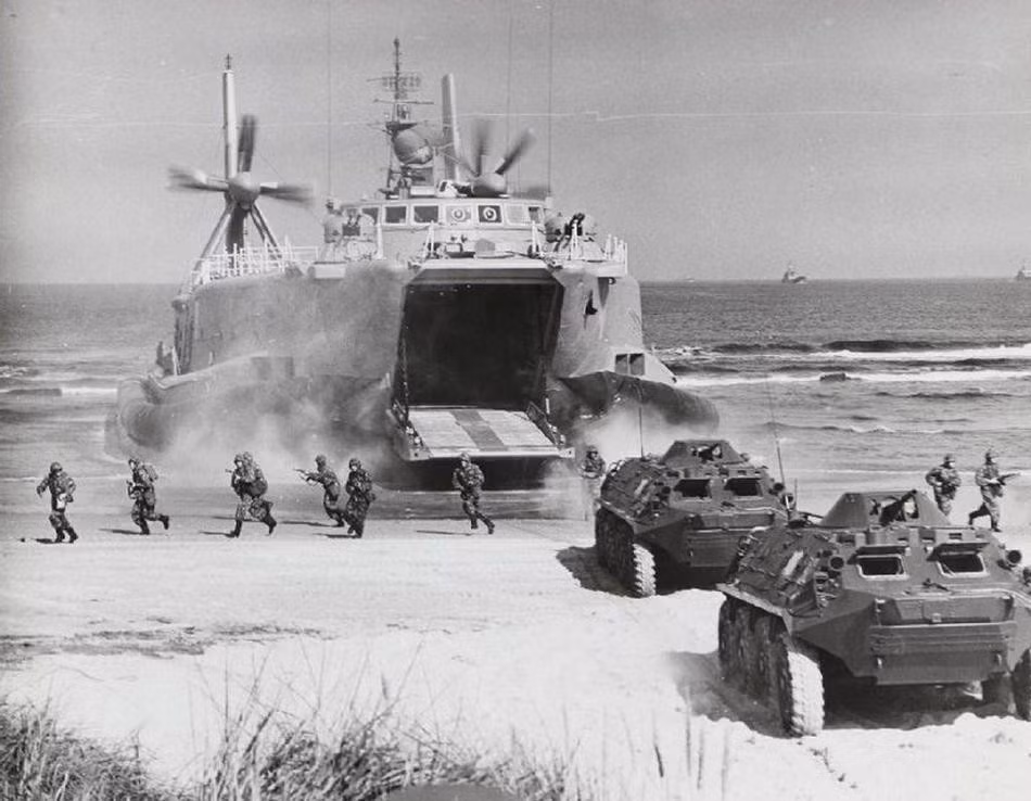 Trong năm 1980, tàu đổ bộ Aist đã thực hiện nhiệm vụ cơ động lực lượng bao gồm cả binh sĩ, xe bọc thép và xe tăng hạng nhẹ đổ bộ lên bãi biển của Đông Đức trong khuôn khổ cuộc diễn tập chung của các quân đội thuộc khối Waszawa. Đây là một hình ảnh cực kỳ đặc biệt và hiếm hoi, không nhiều người có thể biết về việc đây chính là lớp tàu đổ bộ đệm khí đầu tiên được Hải quân Liên Xô sử dụng. Ảnh: Cơ động phương tiện và người từ trong tàu Aist xuống bãi biển của Đông Đức.