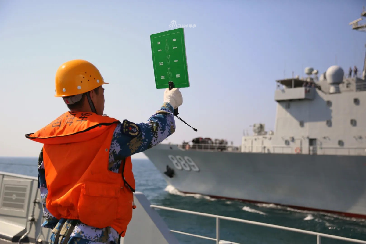 Ảnh: Thủy thủ tàu Type 054A ra ám hiệu liên lạc với tàu vận tải hậu cần số hiệu 889 đang di chuyển song song.