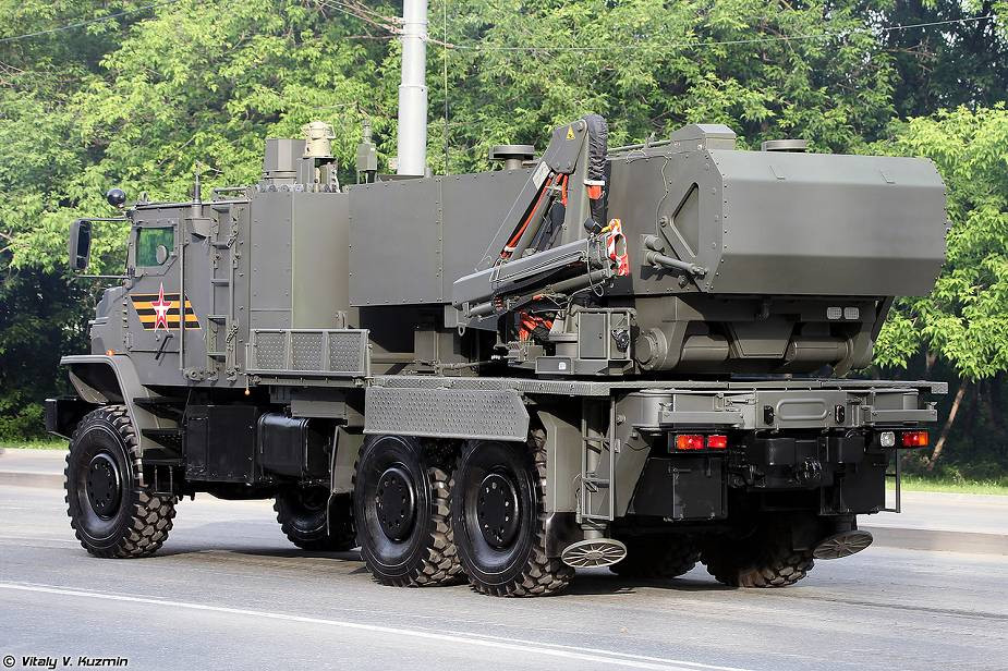 Khác với hệ thống TOS-1A sử dụng xe phóng riêng và xe nạp đạn riêng, hệ thống TOS-2 được tích hợp luôn khả năng tự nạp đạn lên xe phóng với một cần cẩu ở bên trái và một bệ nạp đạn ở bên phải của xe. Ảnh: TOS-2 nhìn từ phía sau, có thể thấy cần cẩu của xe dùng cho nhiệm vụ nạp đạn.