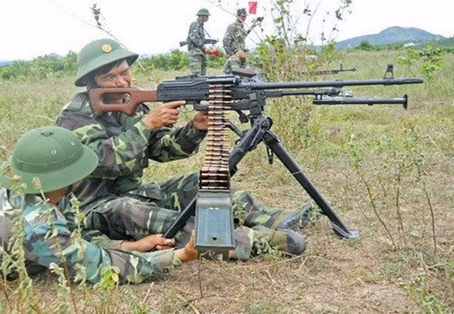 Súng sử dụng 2 loại hộp tiếp đạn: loại 100 viên có khối lượng 3.9kg và loại 200 viên khối lượng 8kg. Ảnh: Chiến sĩ Việt Nam thao tác với súng máy PKM.