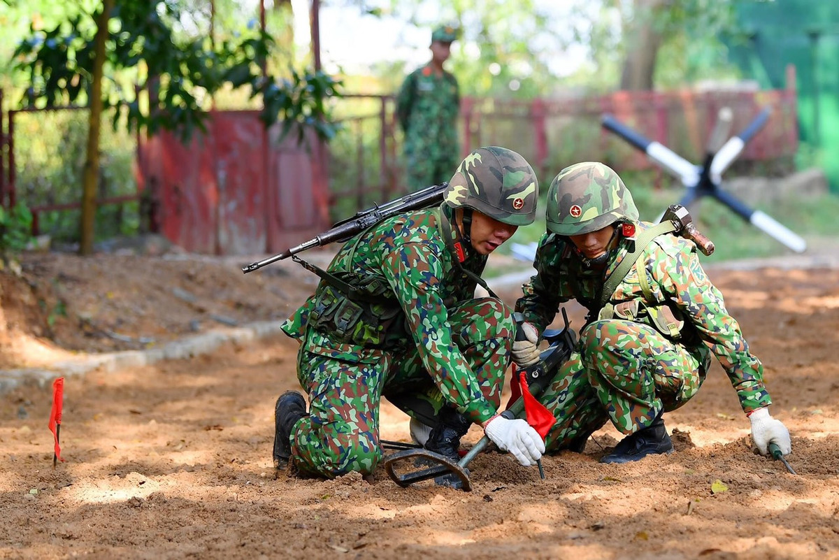 Nội dung phần thi năm nay của Đội tuyển Công binh Việt Nam bao gồm: Tiểu đội công binh xung kích thực hiện đổ bộ từ trực thăng, vượt cầu treo, leo tường lưới, vượt mô hình nhà 2 tầng, dò, phá mìn vượt qua bãi vật cản nổ, tiểu đội bắc cầu cứng TMM-3M2, kíp xe phá dỡ vật cản IMR, kíp xe húc BAT mở đường và vượt chướng ngại vật. Ảnh: Chiến sĩ cắm cờ cảnh báo bom mìn sau khi phát hiện trong quá trình huấn luyện - Nguồn: QĐND.