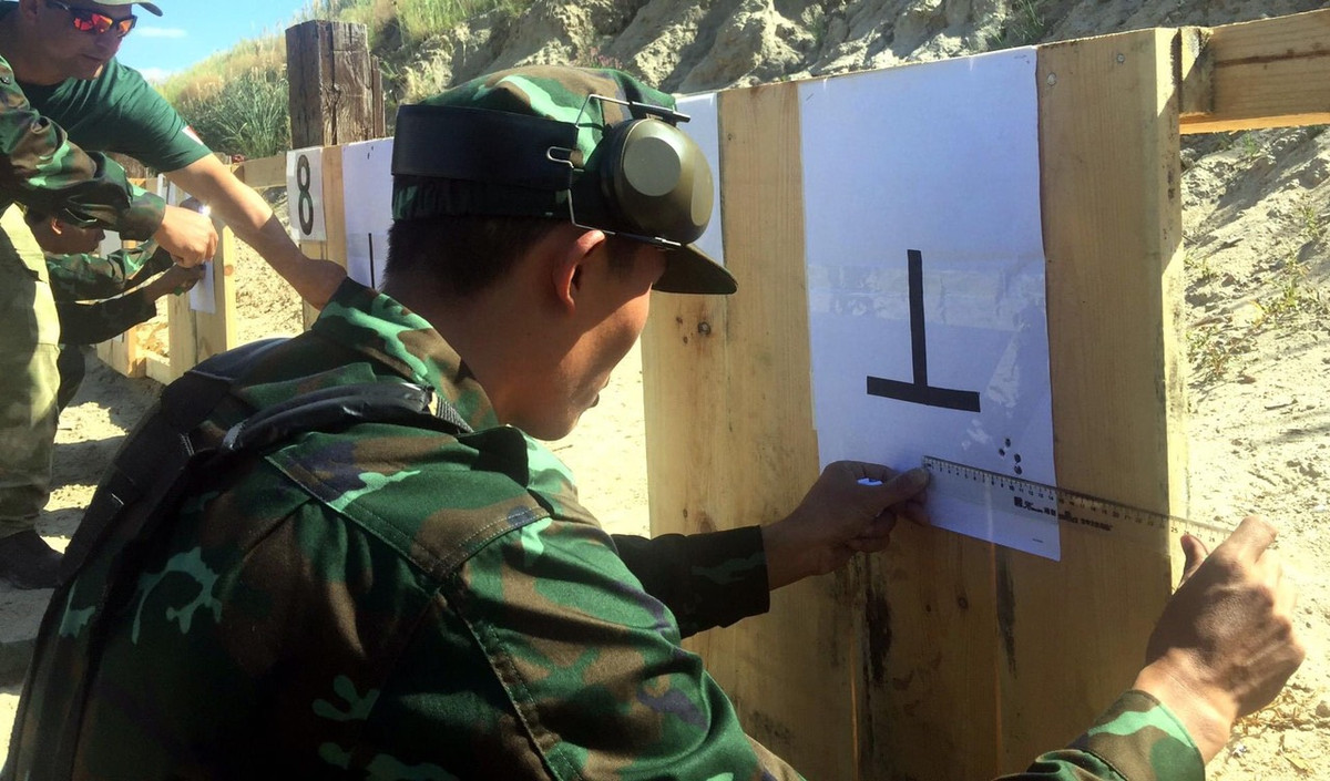 Sau khi có những phát bắn đầu tiên, do kính ngắm của súng vừa được tiếp nhận chưa ở điều kiện chuẩn, do đó các chiến sĩ ta phải bắn nhiều lần, đo đạc chính xác điểm rơi của viên đạn và đường ngắm của kính, sau đó tiếp tục điều chỉnh thông số kính ngắm qua các loạt bắn tiếp theo để có thể đạt được một đường ngắm chính xác nhất trước khi bước vào thi đấu với khẩu súng của mình. Ảnh: Chiến sĩ ta đo độ lệch và điểm rơi của đạn sau loạt bắn từ đó hiệu chỉnh kính ngắm - Nguồn: QĐND.